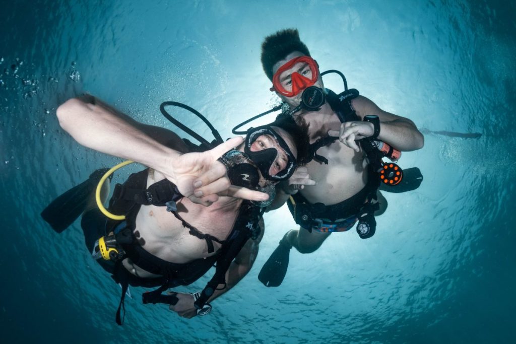 2 men scuba diving looking down at camera