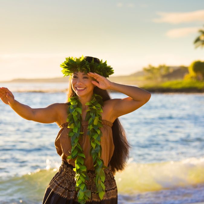 hawaiian girl dancing on beach with waves behind her