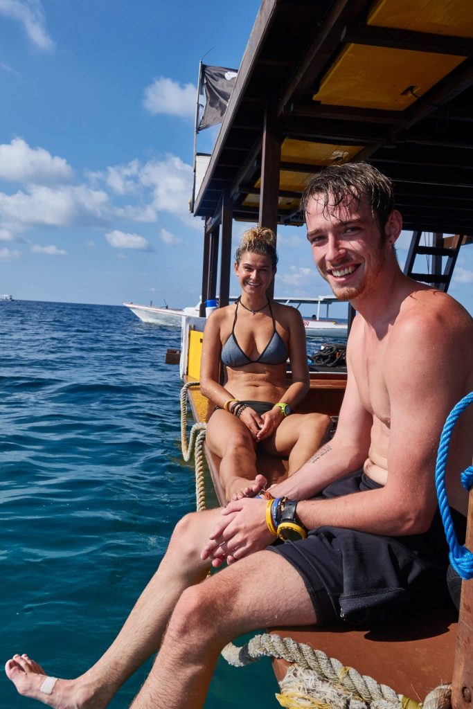 man and woman sat on scuba boat with legs hanging off