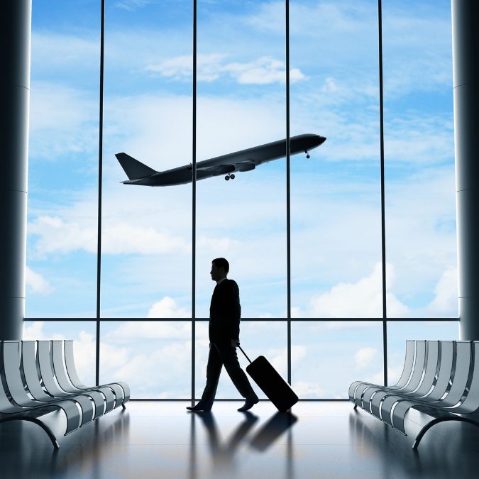 man walking at airport with plane flying over head