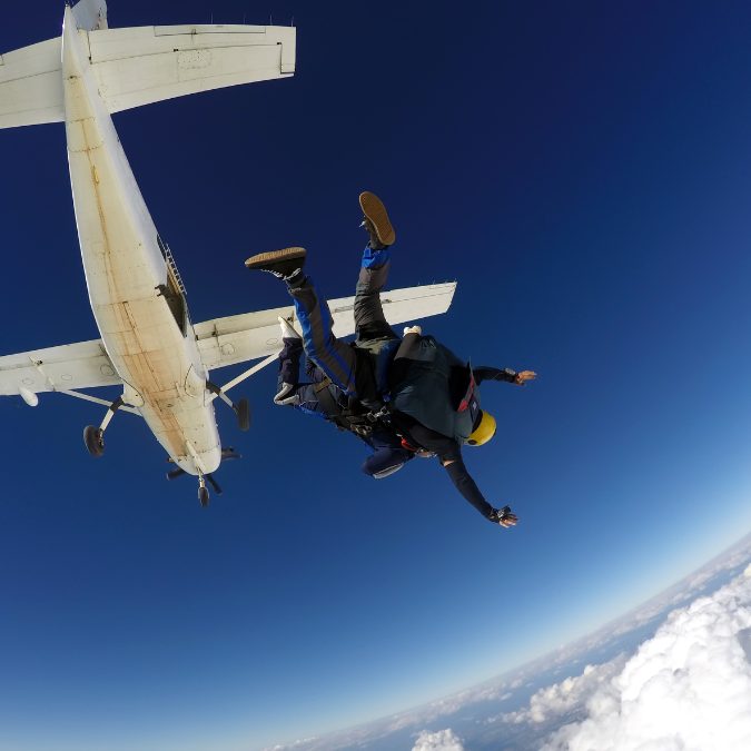 2 people jumping out of the plane tandem with plane in the background 