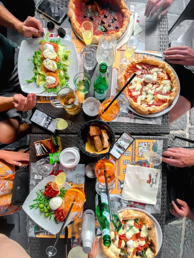 top down view of pizza and salads at a restaurants with aperol spritz in rome italy