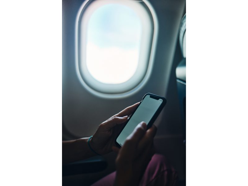 person on phone in airplane seat with window in background