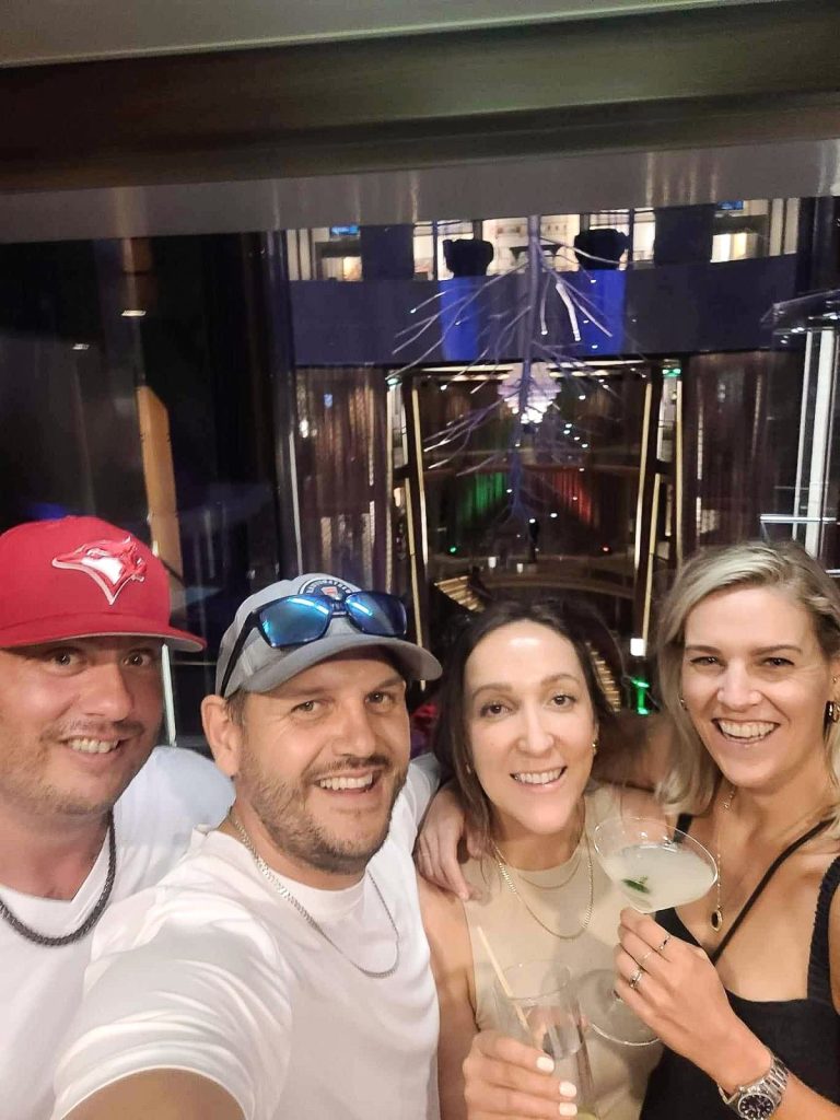 4 people smiling with drinks taking a photo on celebrity cruise ship