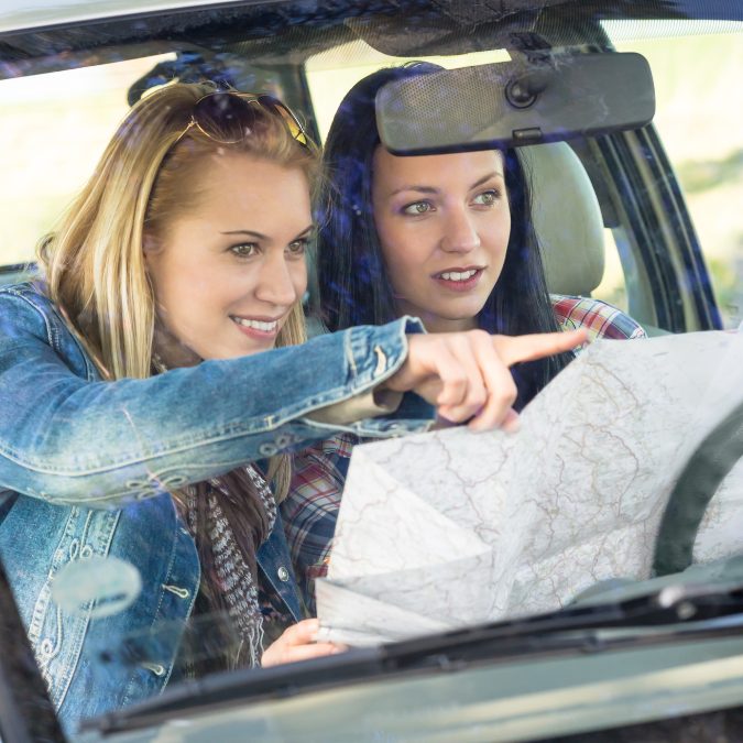 sisters with map going on a family road trip 
