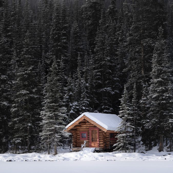 little cabin in the woods with snow on roof 