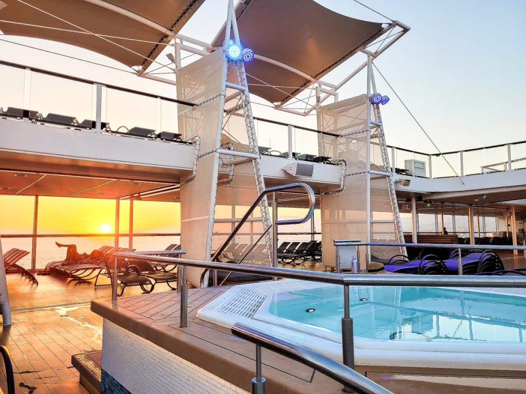 photo of cruise ship with sun setting in background and pool in foreground