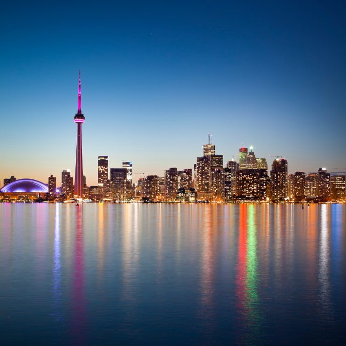skyline of toronto at dusk with water in foreground 