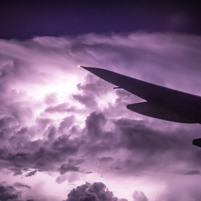 wing of aircraft with a thunderstorm in the background can a plane fly in a thunderstorm