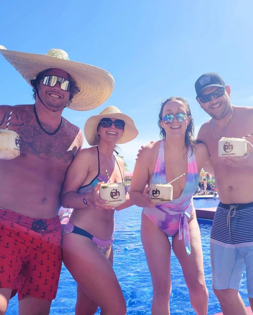 4 adults with coconuts in their hands at all inclusive resort in cancun Mexico