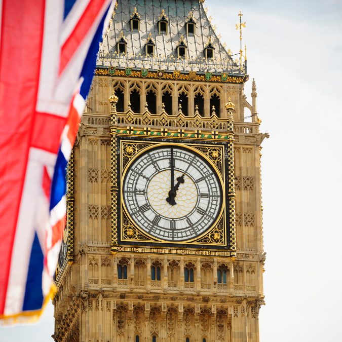 close up of clock tower in london with flag in foreground 