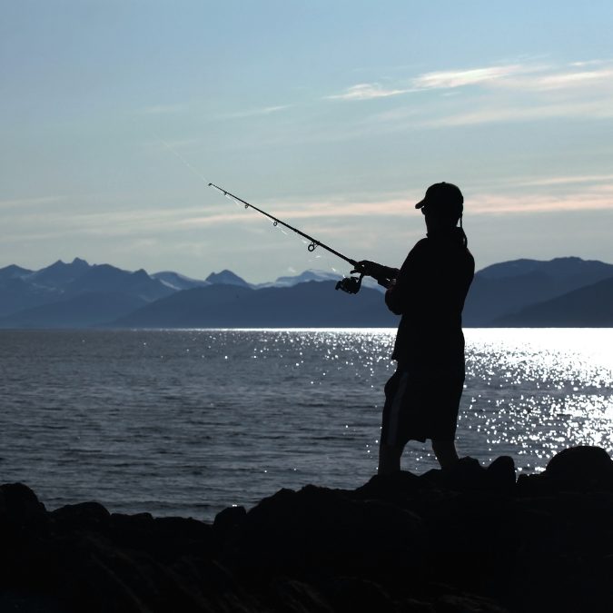 fisherman in alaska holding a fishing rod