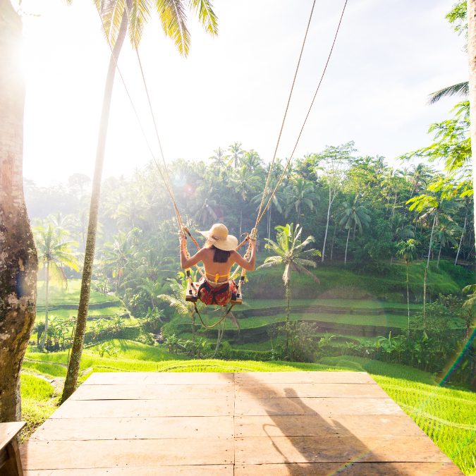 woman on balinese swing in the rice terraces in bali 