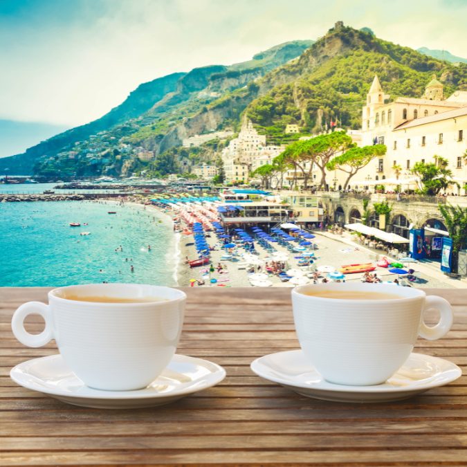 2 cups of coffee in foreground with beach and mountain in background