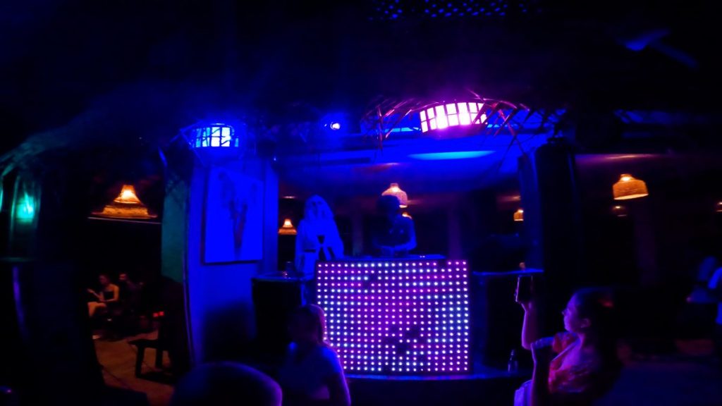2 dj's behind a dj booth lit up with blue lights