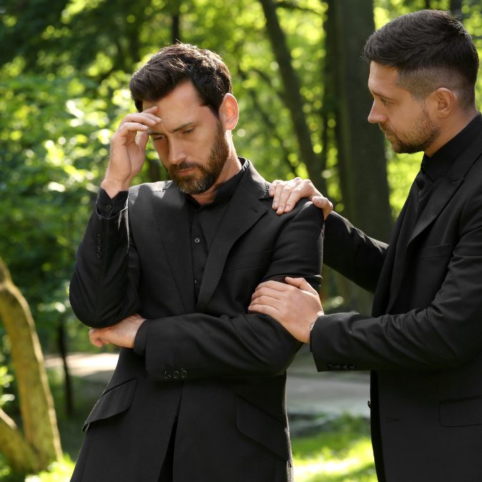 one man consoling another man at a funeral 