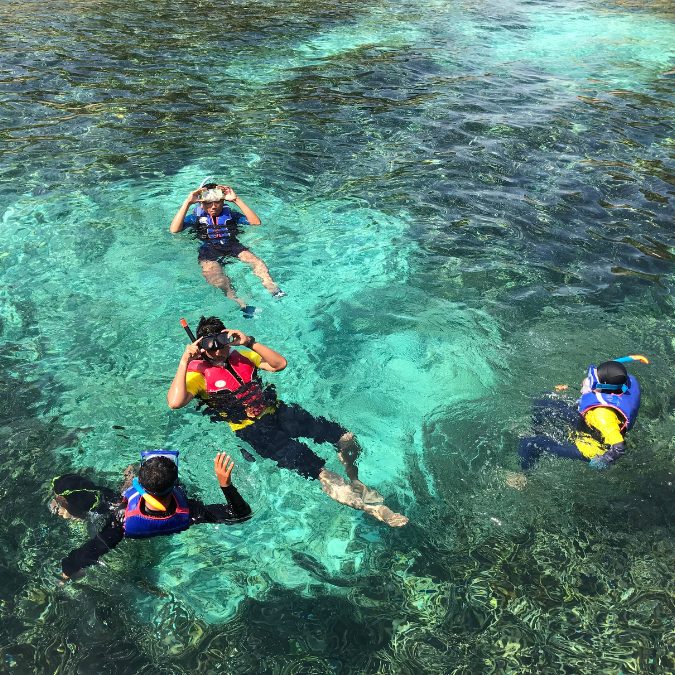 4 people in turquoise water snorkeling 