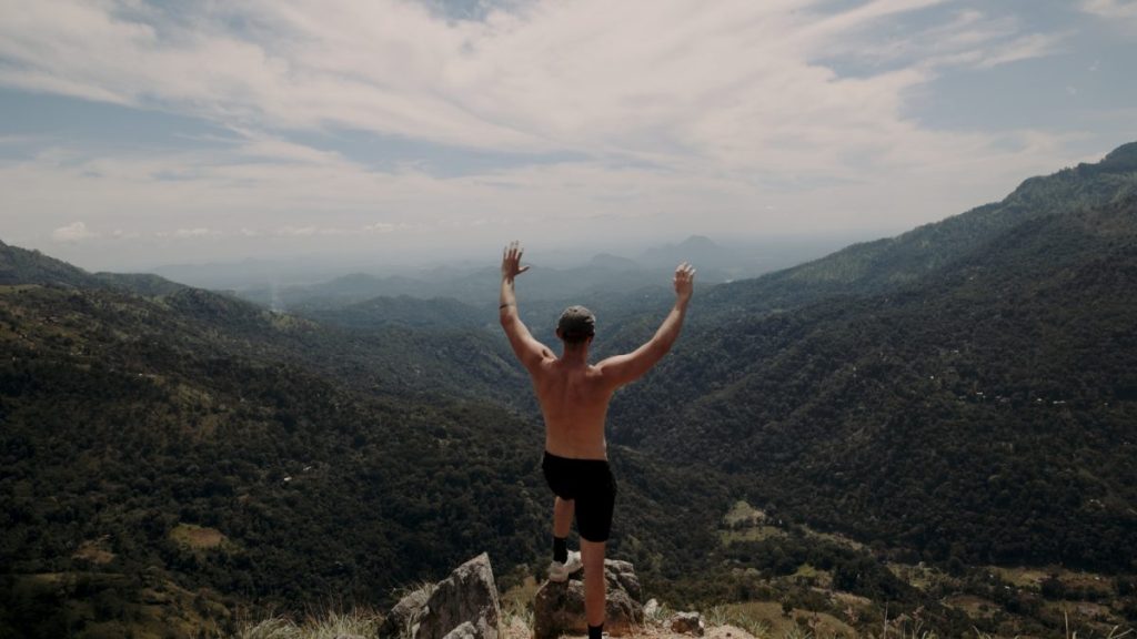 man on the peak of little adams peak with his arms in the air 