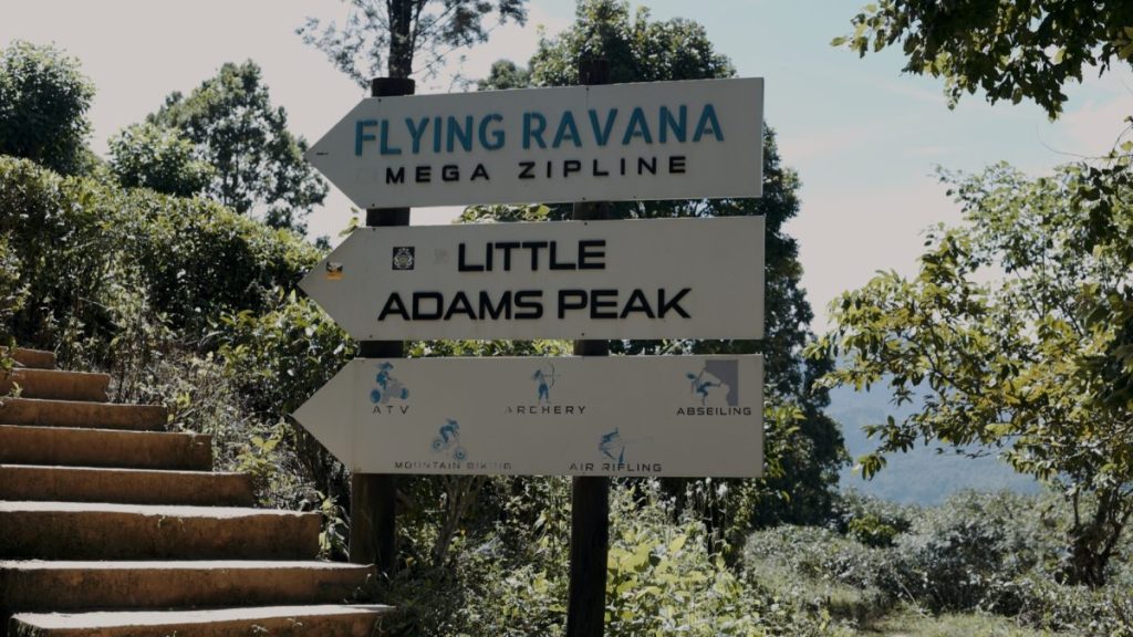 multiple signs with little adams peak pointing up the mountain 