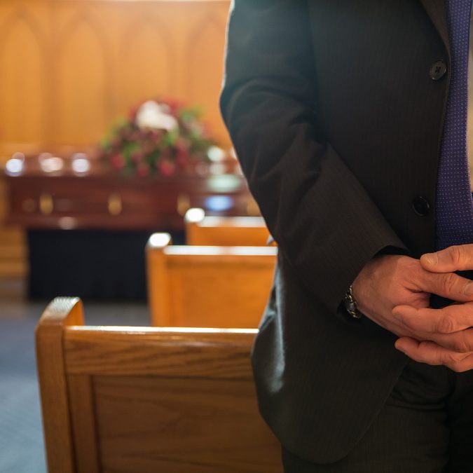man at funeral with hands together