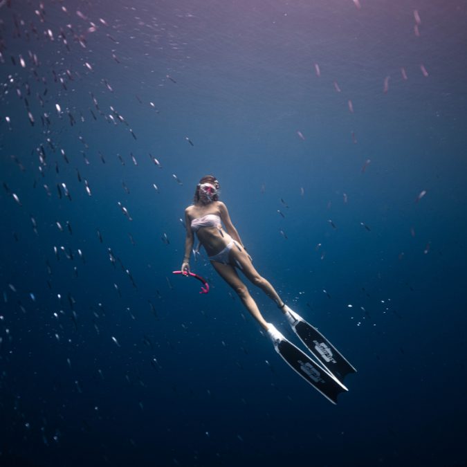 woman holding a snorkel in the blue sea with fins on  