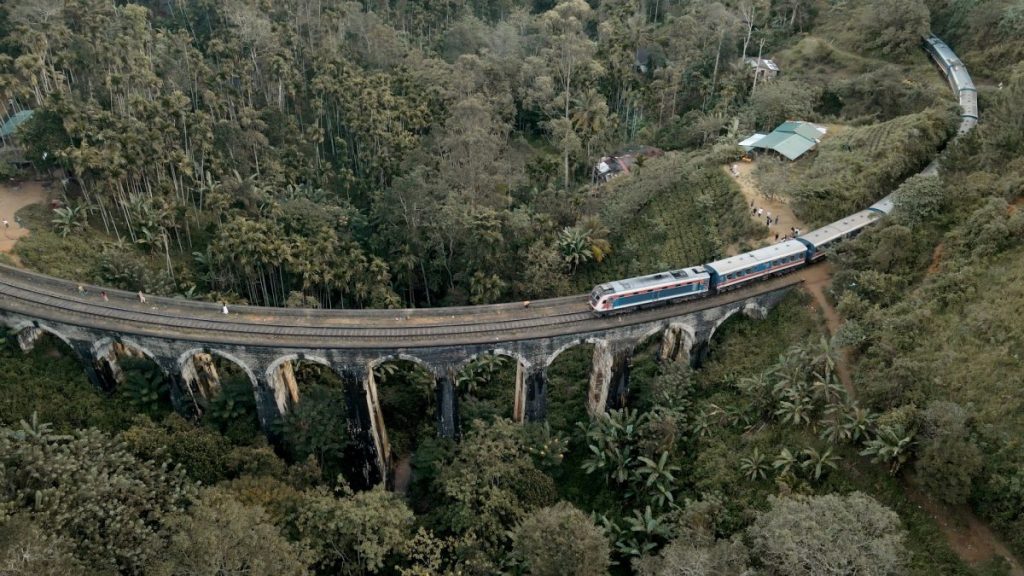 famous blue train on the nine arch bridge surrounded by green jungle 
