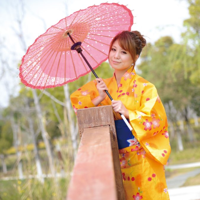 japanese woman with yellow dress and pink umbrella