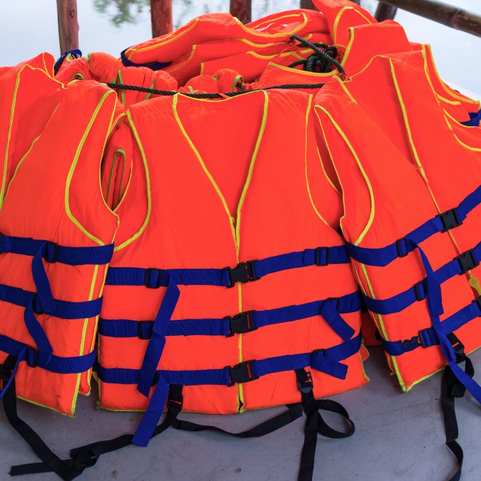 multiple orange life jackets wrapped together on a boat 