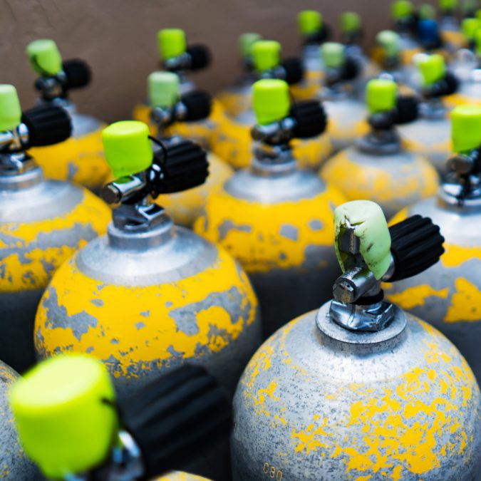 multiple yellow scuba tanks with green caps 