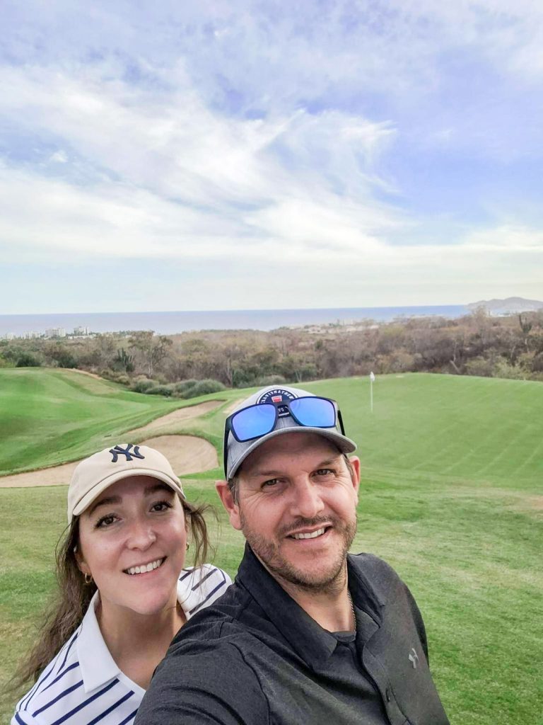 couple taking a selfie at San Jose del cabo golf course with ocean in background