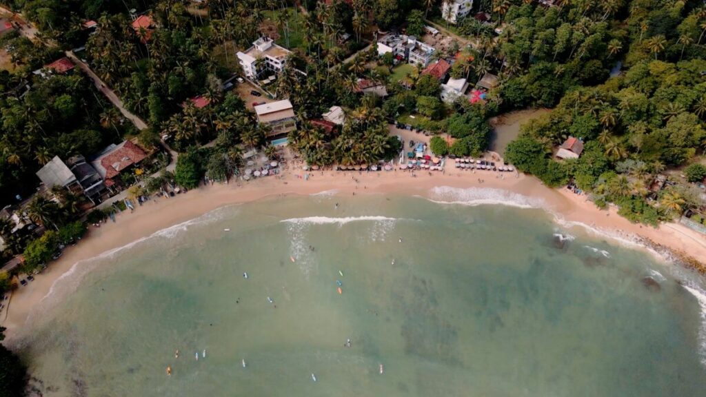 top down shot of hiriketiya's beach with green water and green trees