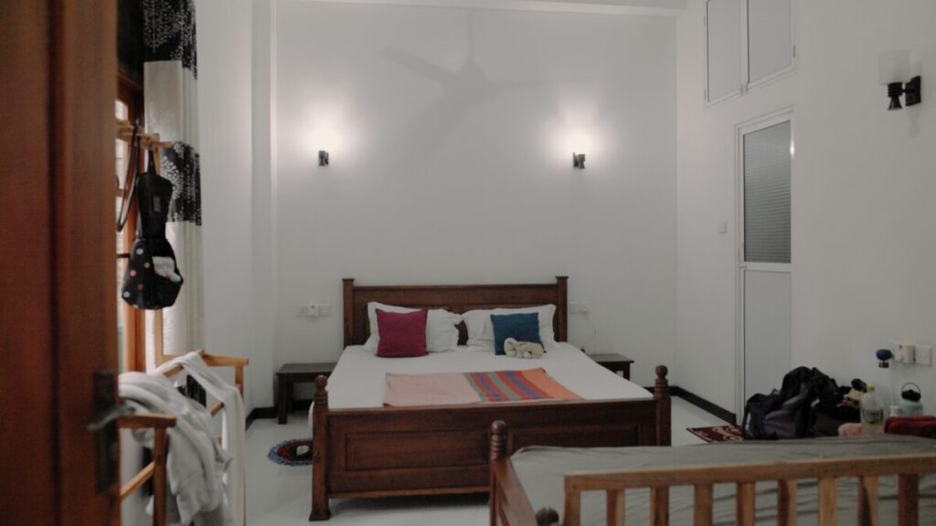 white room with a double bed with two lights behind it 
