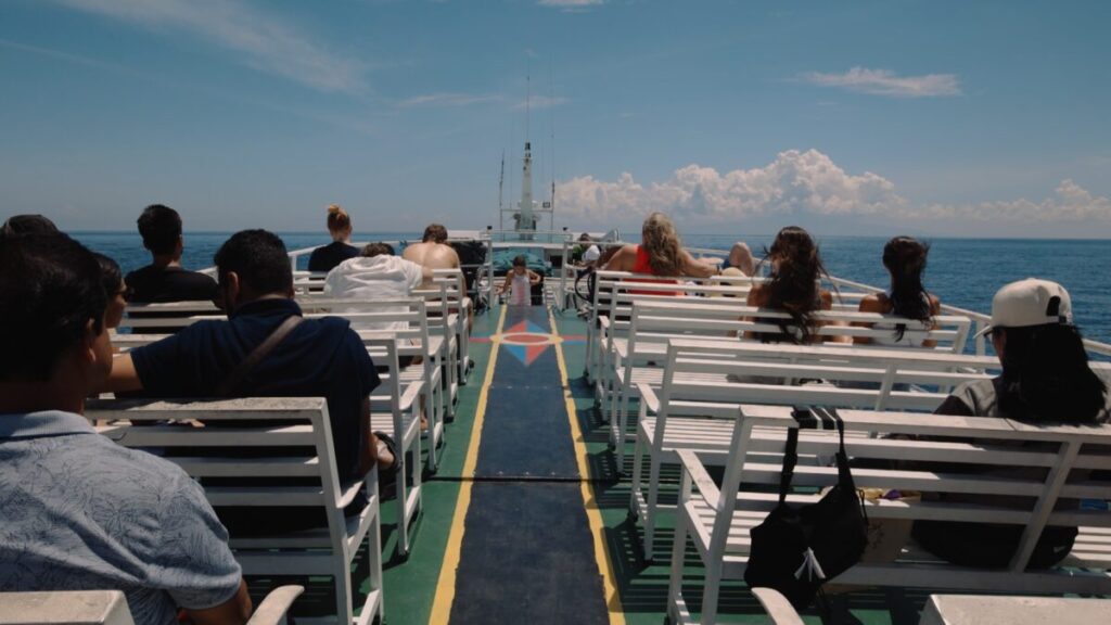 big ferry with passengers sitting on white benches