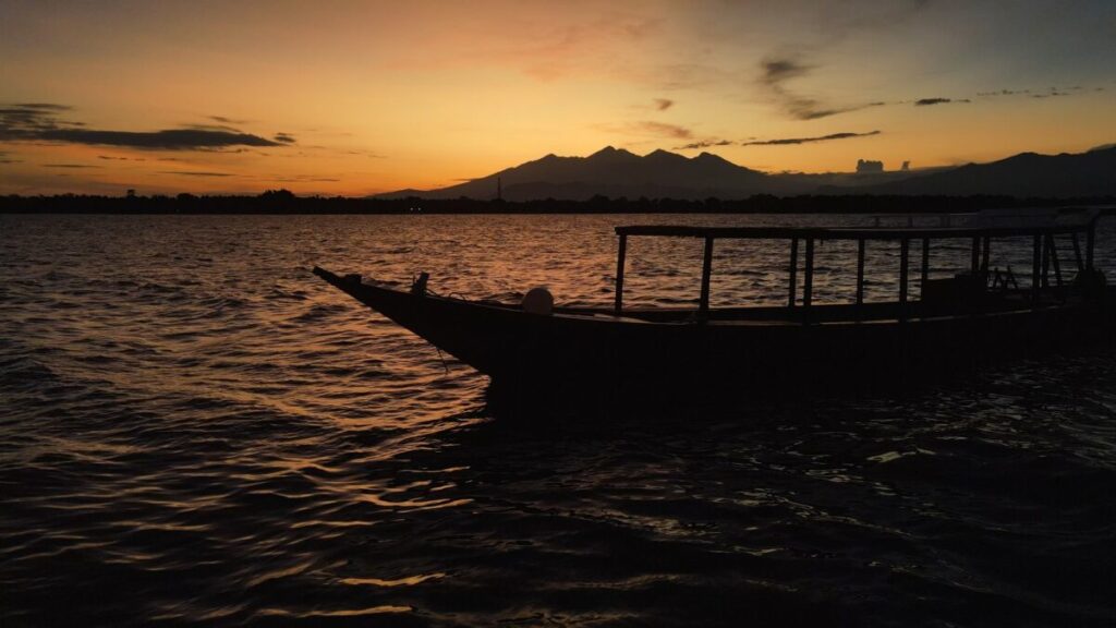 sunrise in gili t with a dive boat and mountains in the back ground 